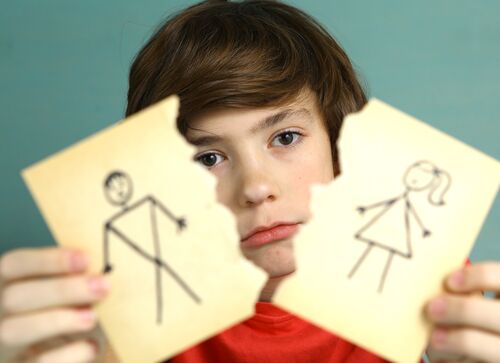 sad preteen boy unhappy about parents divorce, hold man and woman paper drawing torn apart