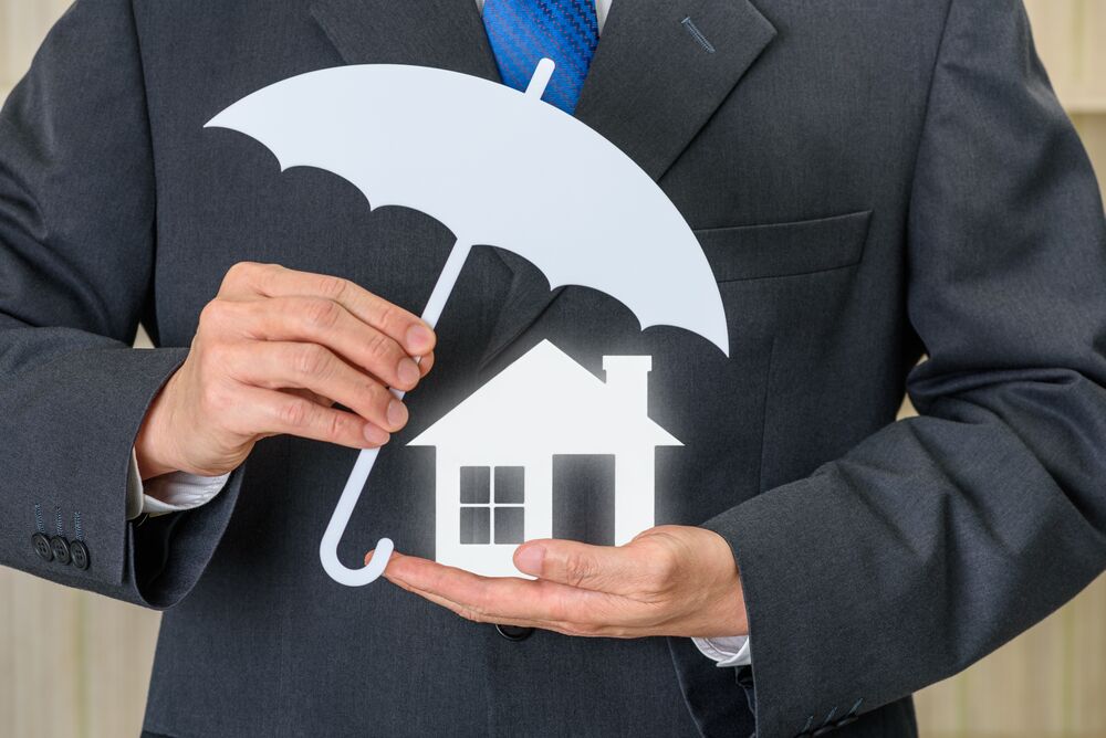 Protection from mortgage foreclosure and land contract forfeiture, business concept : Businessman protects a home or a house, depict protecting a borrower or buyer from failing to pay money to lender