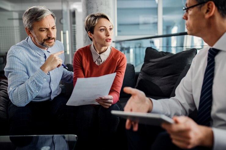Three professionals in a discussion during a meeting about divorce without a lawyer in Texas, with paperwork and a digital tablet.