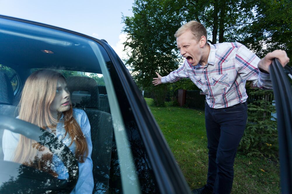Young man screaming at a woman in car