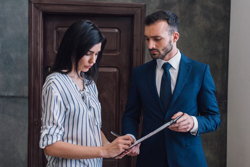 Woman writing in documents in male hands in room