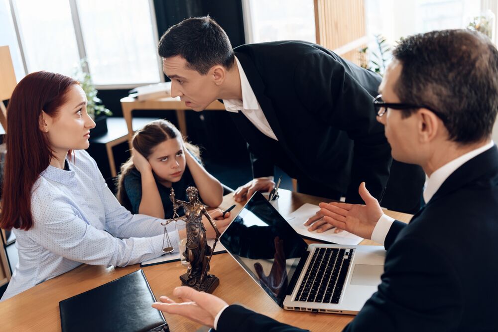 Cute girl closes ears when parents quarrel in lawyer's office. Girl's parents are getting divorced. Dissolution of marriage of two adults.