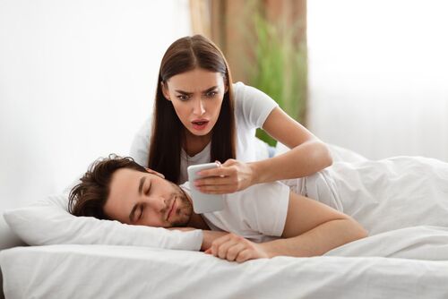 Infidelity divorce law. Shocked Wife Reading Message From Lover On Phone While Cheating Husband Sleeping In Bedroom At Home. Jealous Woman Checking Boyfriend's Cellphone Chats. Affair, Relationship Issues