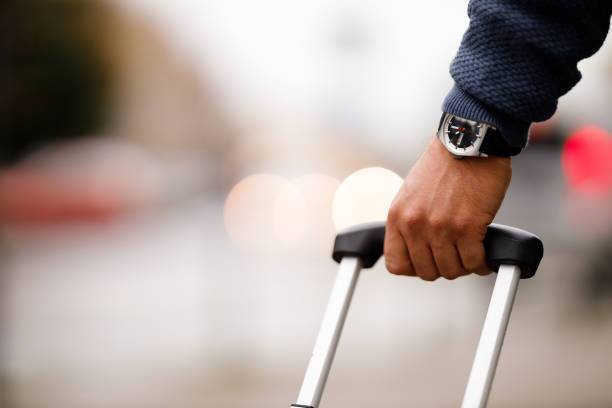 Close up of a man's hand with a watch holding the luggage Close up of a man's hand with a watch holding the luggage, blurred background. divorce time stock pictures, royalty-free photos & images
