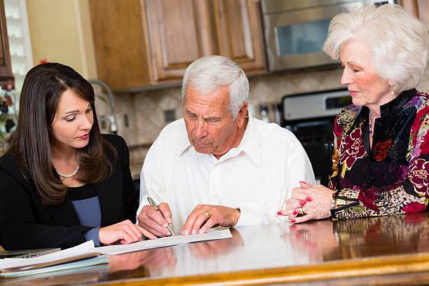 Professional with Clients A business woman working with her senior citizen clients. will signing brown stock pictures, royalty-free photos & images