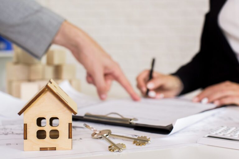 Brown wooden cottage with keys, in the background the woman is signing a paper