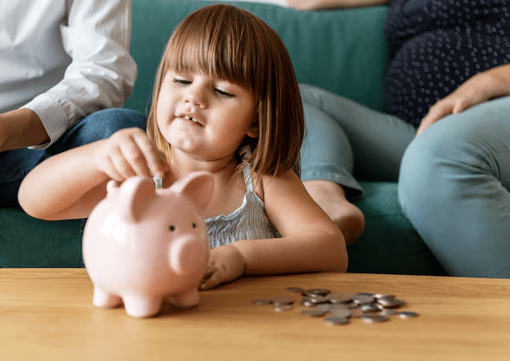 A young girl places coins into a pink piggy bank while sitting at a table, as adults—perhaps discussing how child support is calculated in Texas—are seated on a couch in the background.
