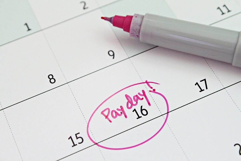 A close up of an empty calendar that only says pay day in pink on the 16th and it is circled