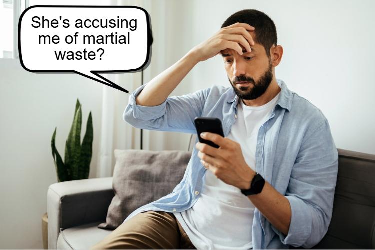 A man sits on a couch, looking concerned at his phone, with a speech bubble saying, "She's accusing me of marital waste during our divorce?.