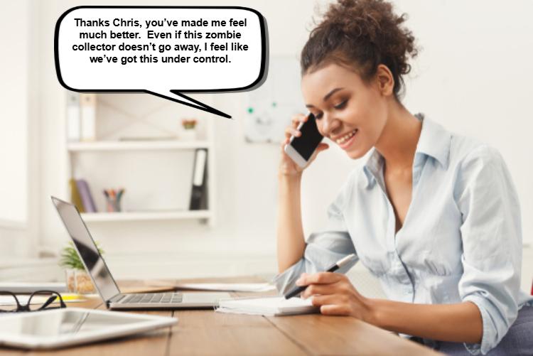 A woman sits at a desk with a laptop, writing in a notebook while talking on the phone. 