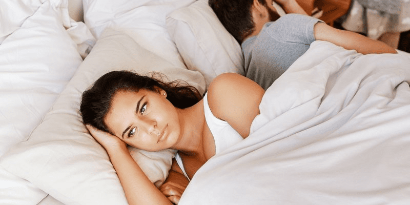 A woman lays in bed next to her husband, contemplating divorce.
