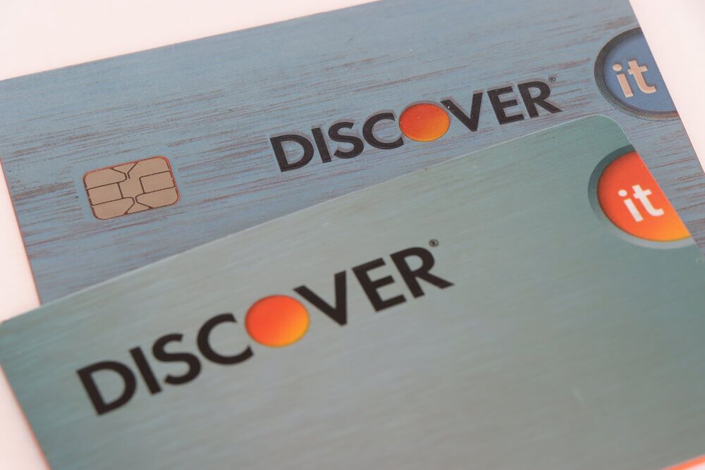 Two blue Discover cards stacked laying on a white surface