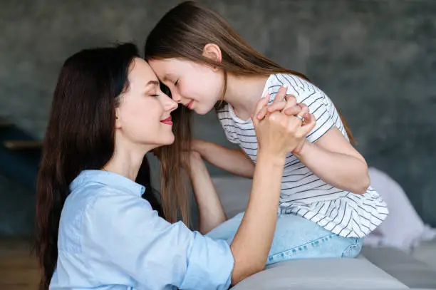 Mother and daughter holding hands and touching foreheads