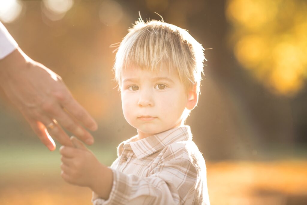 Child staring at the camera and holding on to parent's ring finger