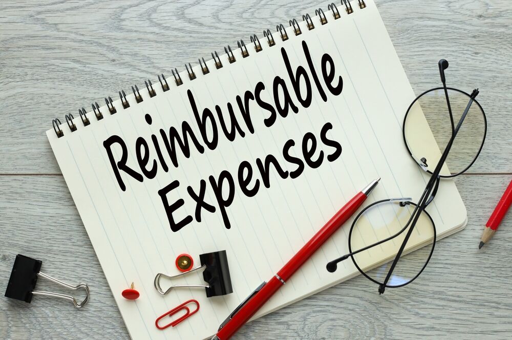 reimbursable expenses. light wooden background. text on a notepad. red pencil and paper clips