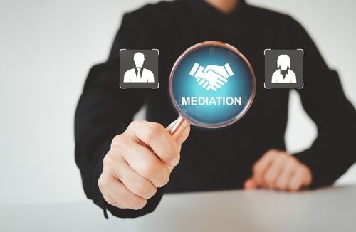 Man holding up a magnifying glass that says "Mediation"