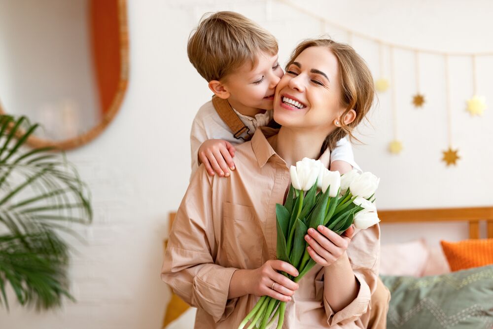 mother's day mom hugging her child with flowers in hand