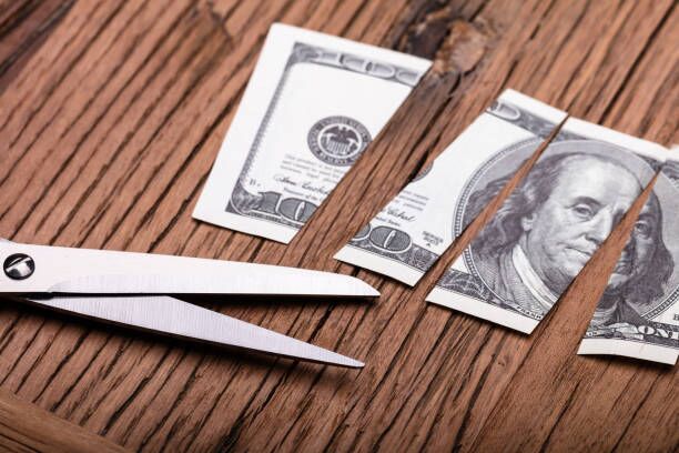 $100 bill cut into four pieces with scissors sitting next to it