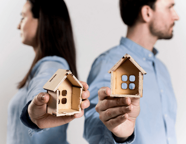 A man and woman holding house models in their hands.